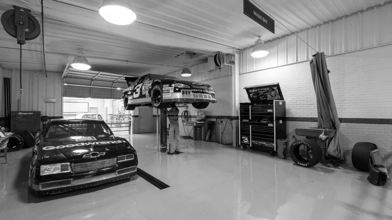 Voitures de course anciennes en cours d'entretien dans un garage, présentant l'histoire et l'ingénierie de l'automobile.