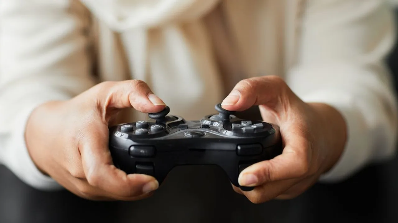 Gros plan sur une personne tenant une manette de jeu vidéo, en mettant l'accent sur l'interaction des mains.