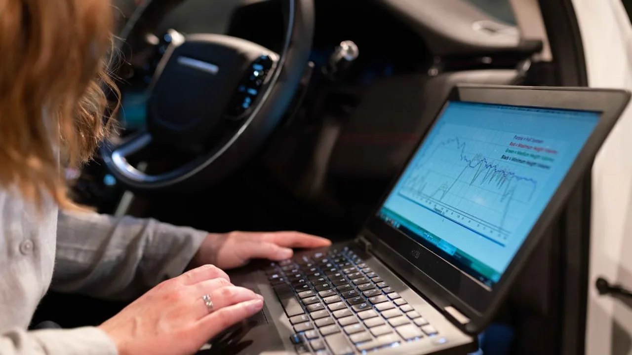 Ingénieure utilisant un ordinateur portable pour analyser les données du véhicule à l'intérieur d'une voiture à des fins de test.