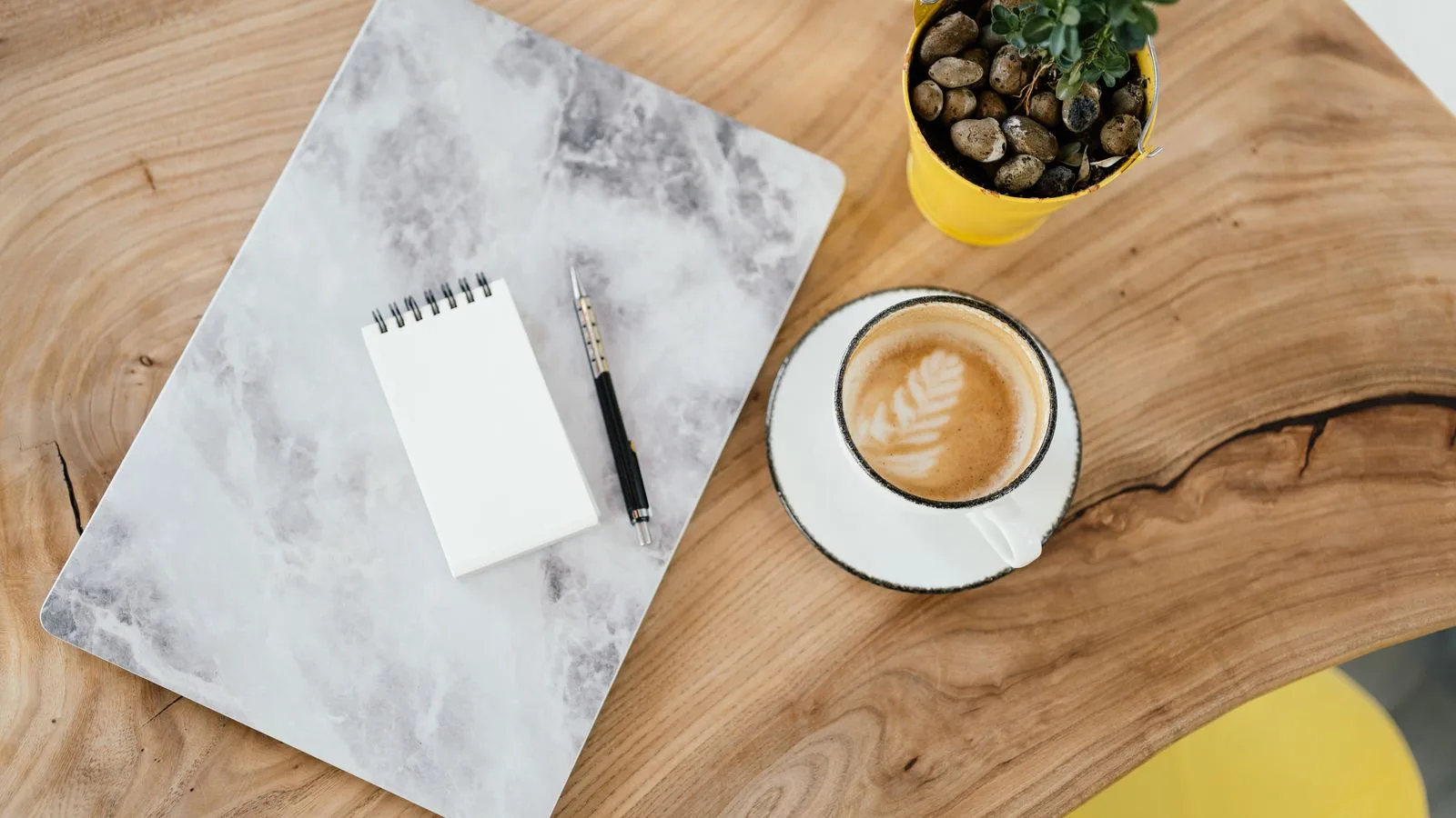 Bloc-notes, café et petite plante sur un bureau en bois