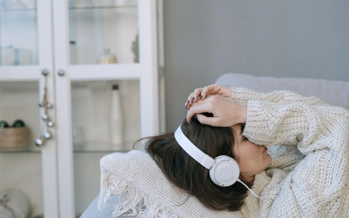 Une personne allongée dans un pull épais, un casque audio sur les oreilles